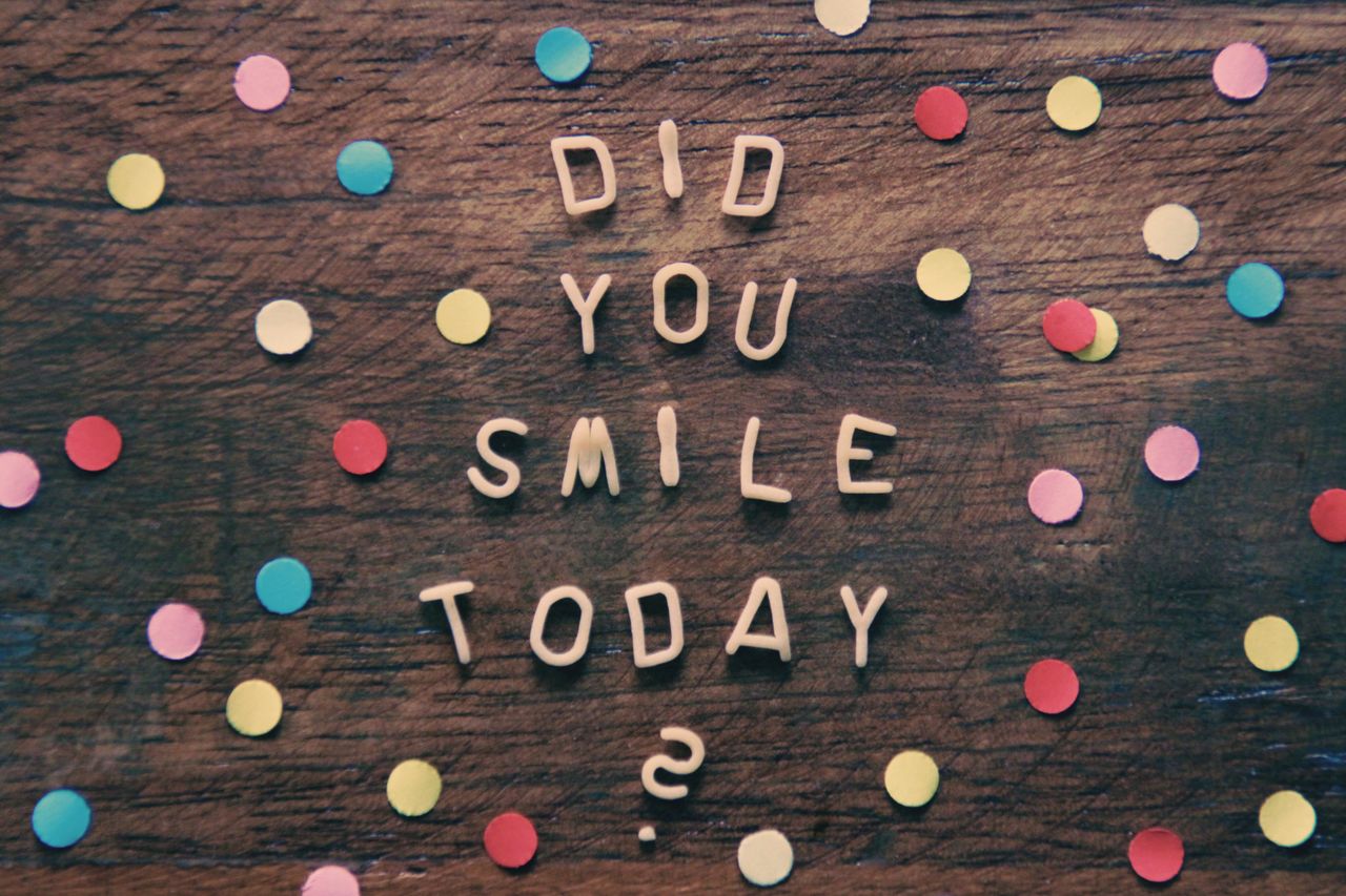 Bright confetti and inspiring text on wooden background with a question: Did you smile today?